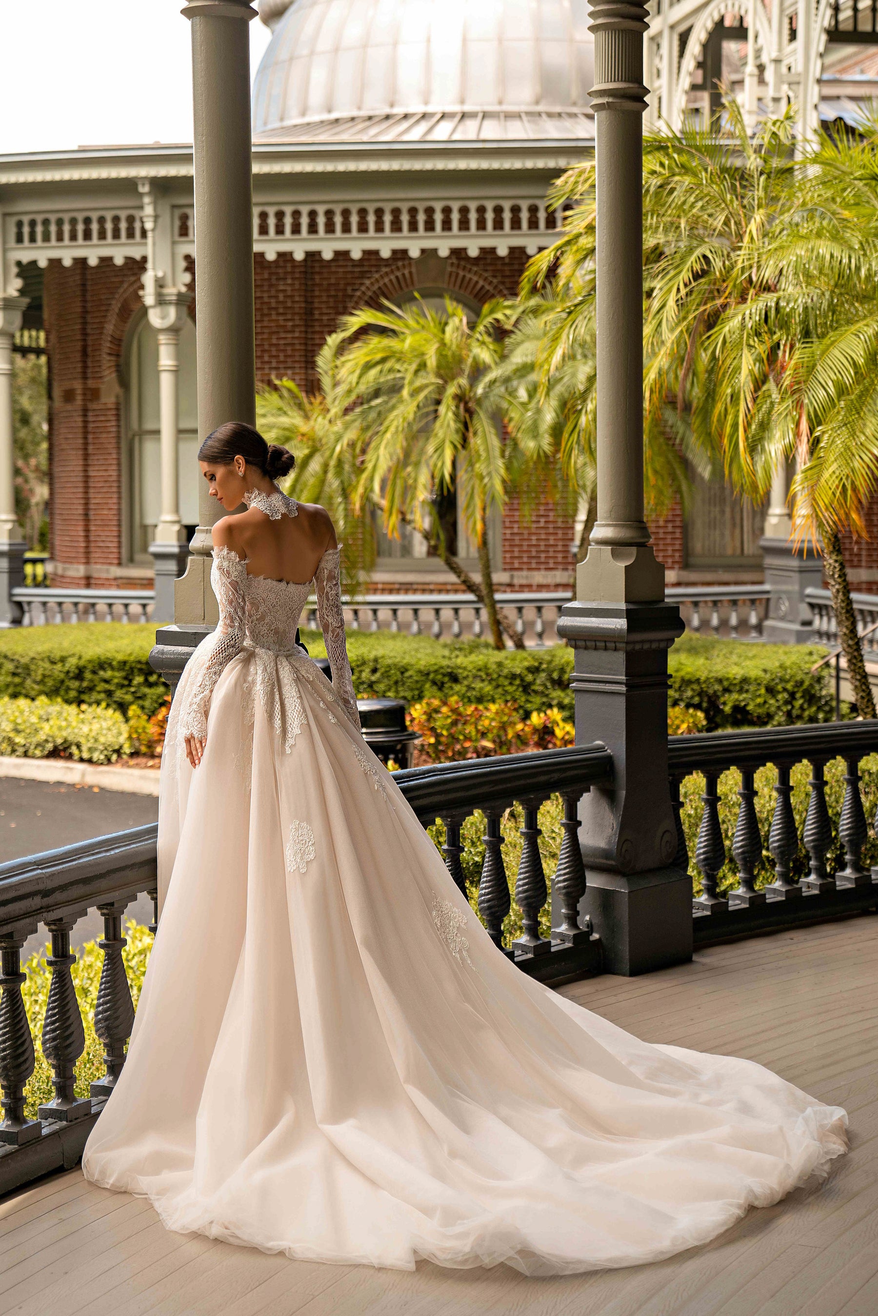 Ivory lace wedding dress with long sleeves, fitted bodice, flowing skirt, and an extended train