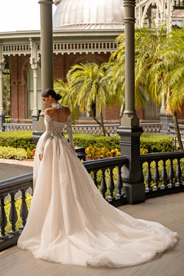 Ivory lace wedding dress with long sleeves, fitted bodice, flowing skirt, and an extended train