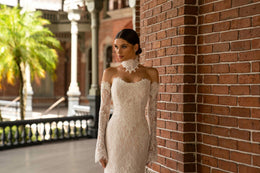Close-up of an ivory lace wedding dress with fitted long sleeves and an off-the-shoulder neckline