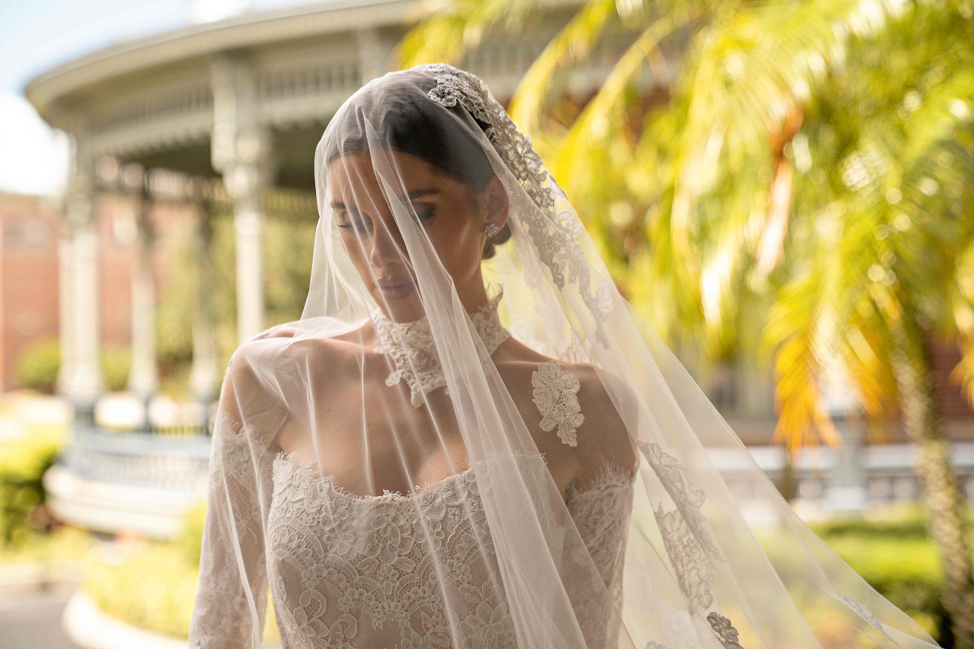 Close-up of an ivory lace wedding dress bodice with long sleeves, square neckline, and sheer veil