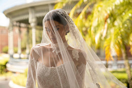 Close-up of an ivory lace wedding dress bodice with long sleeves, square neckline, and sheer veil
