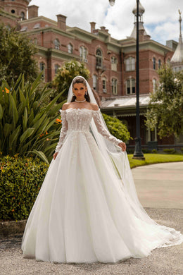 Ivory A-line wedding dress with an off-the-shoulder neckline, floral bodice, sheer lace sleeves, and a long train