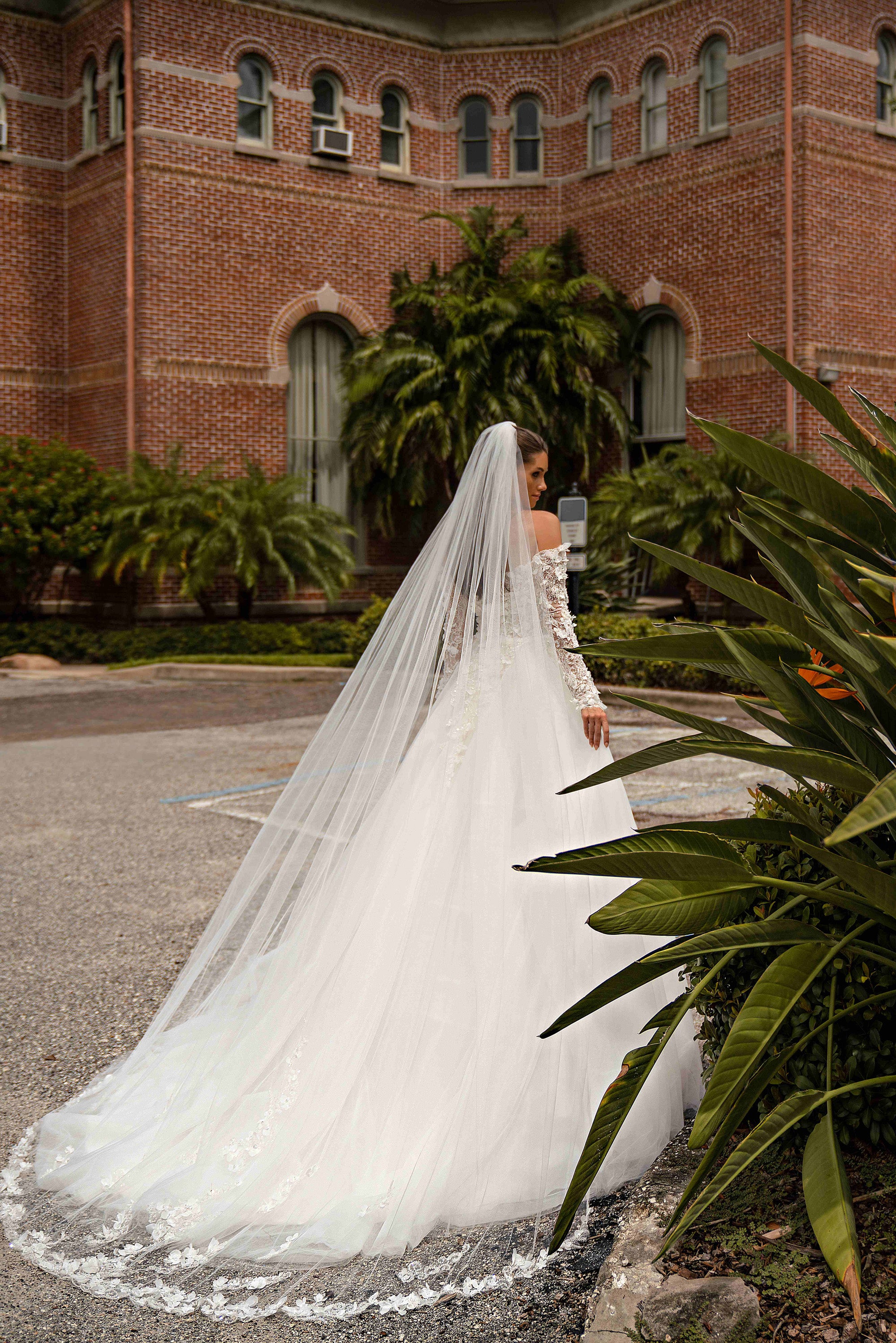 Side view of an ivory wedding dress with a full A-line skirt, long train, and long sheer lace sleeves