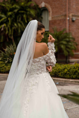Open upper back and floral lace detailing on an ivory off-the-shoulder wedding dress with long sheer sleeves