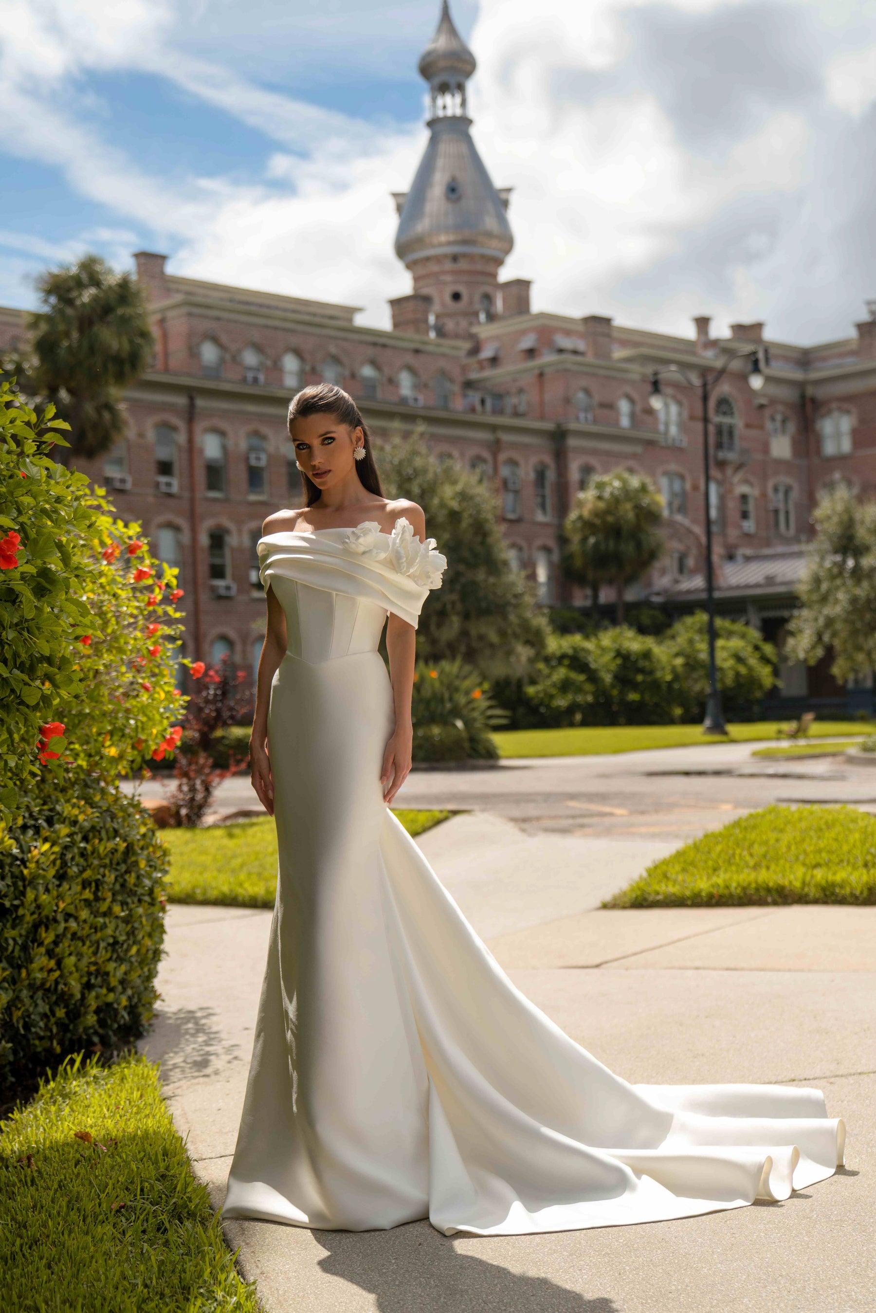 Ivory mermaid wedding dress with an off-the-shoulder draped neckline and sweeping train
