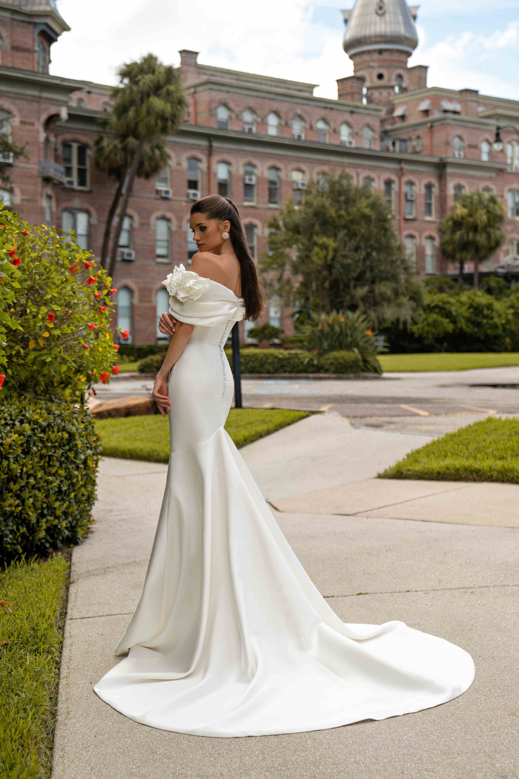 Side view of an ivory mermaid wedding dress with an off-the-shoulder floral neckline and long train