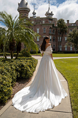 Back view of an ivory A-line wedding dress showing the draped neckline, lace-decorated waist, and sweeping train