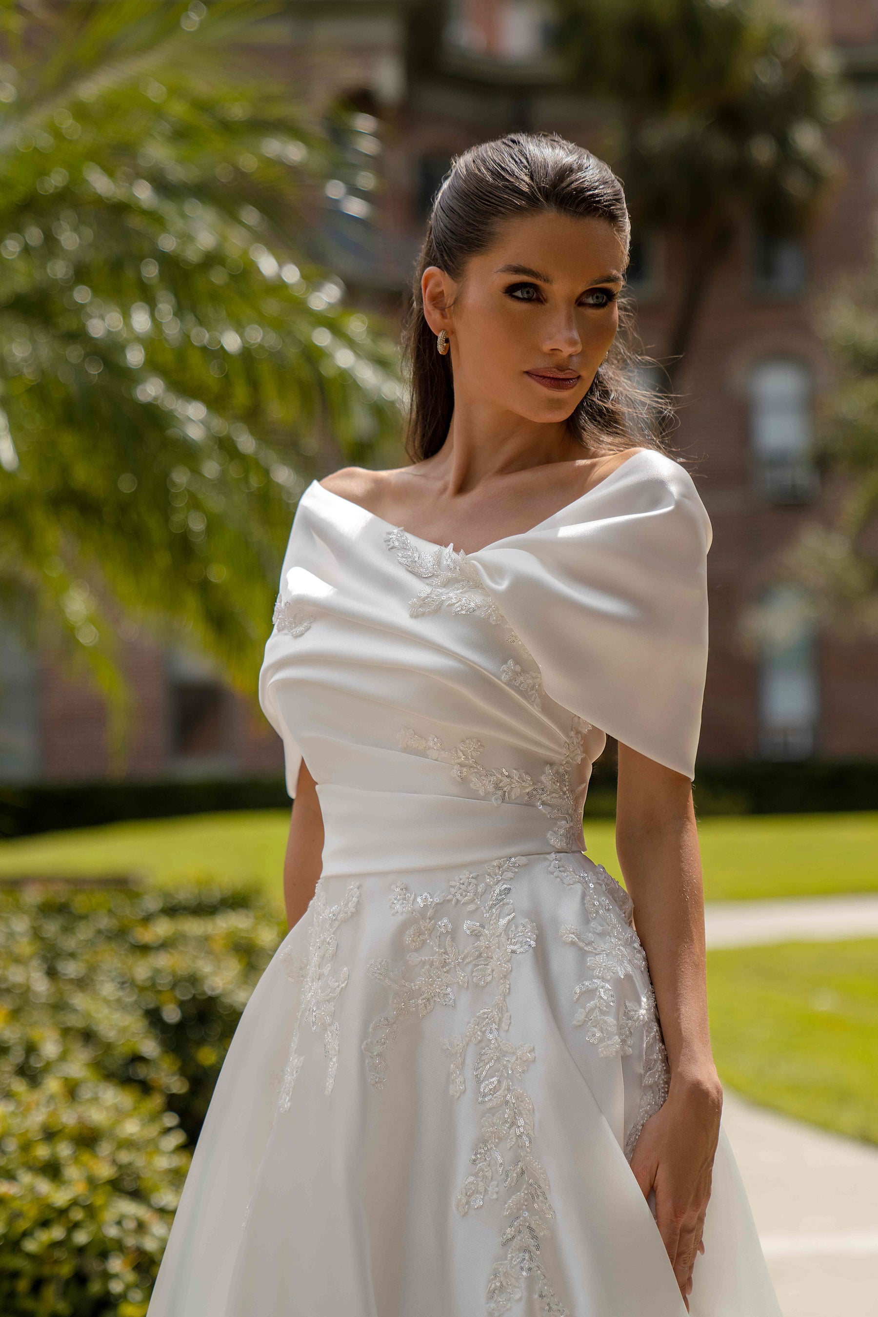 Close-up of an ivory wedding dress bodice with draped off-the-shoulder neckline and floral lace appliqués
