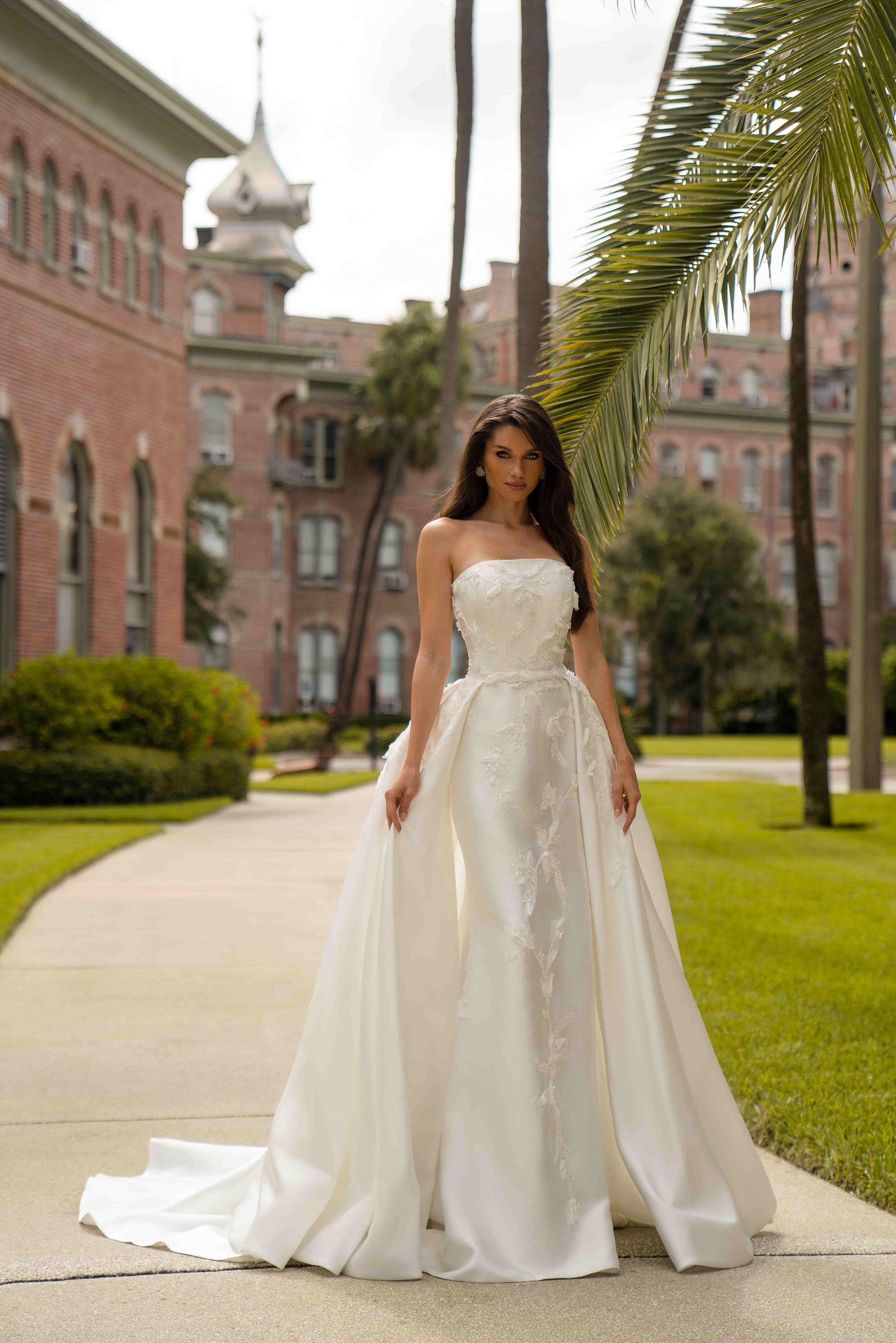 Ivory strapless wedding dress with a fitted embroidered skirt and detachable overskirt panels