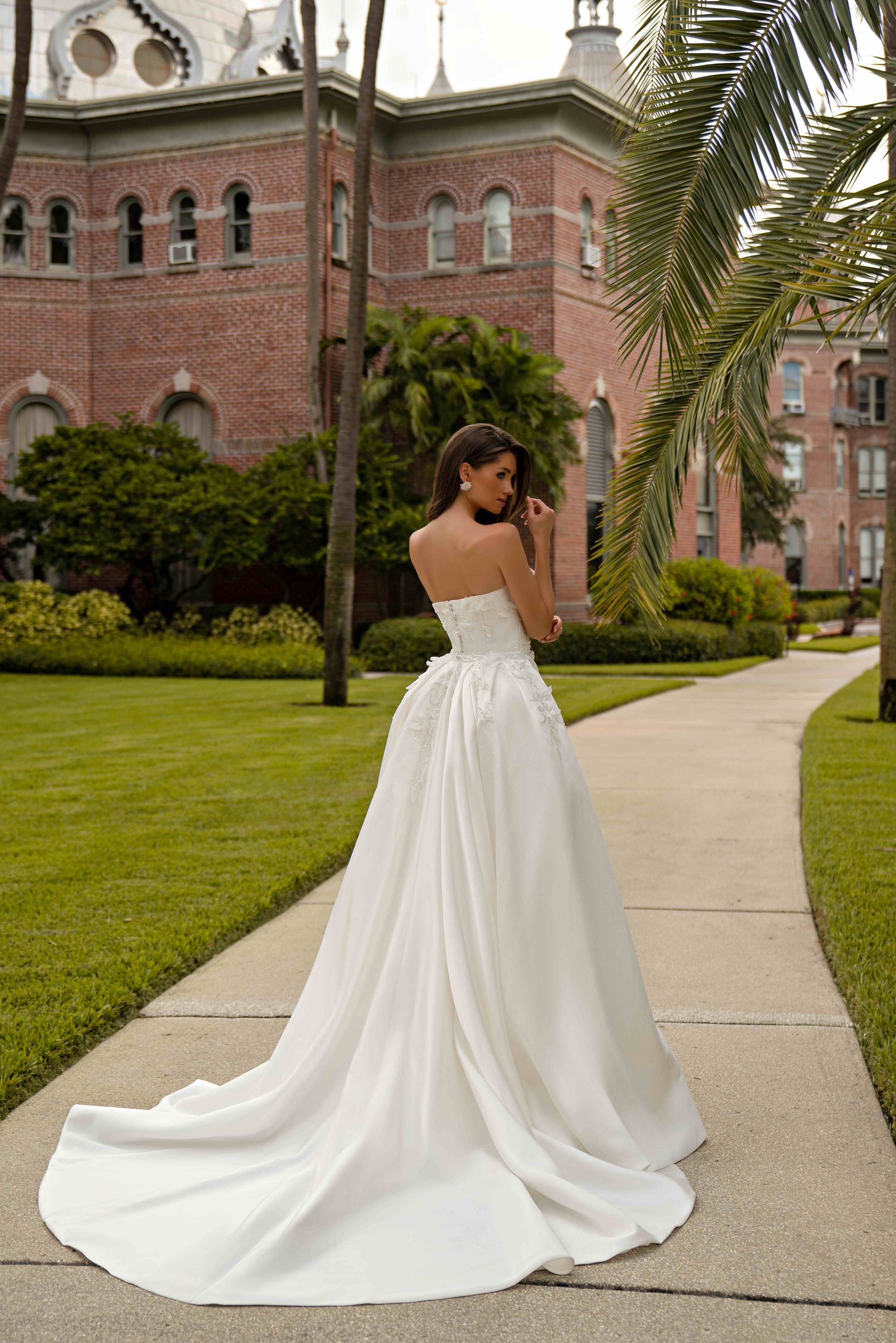 Ivory strapless wedding dress shown with a detachable full overskirt, gathered draping, and a long train
