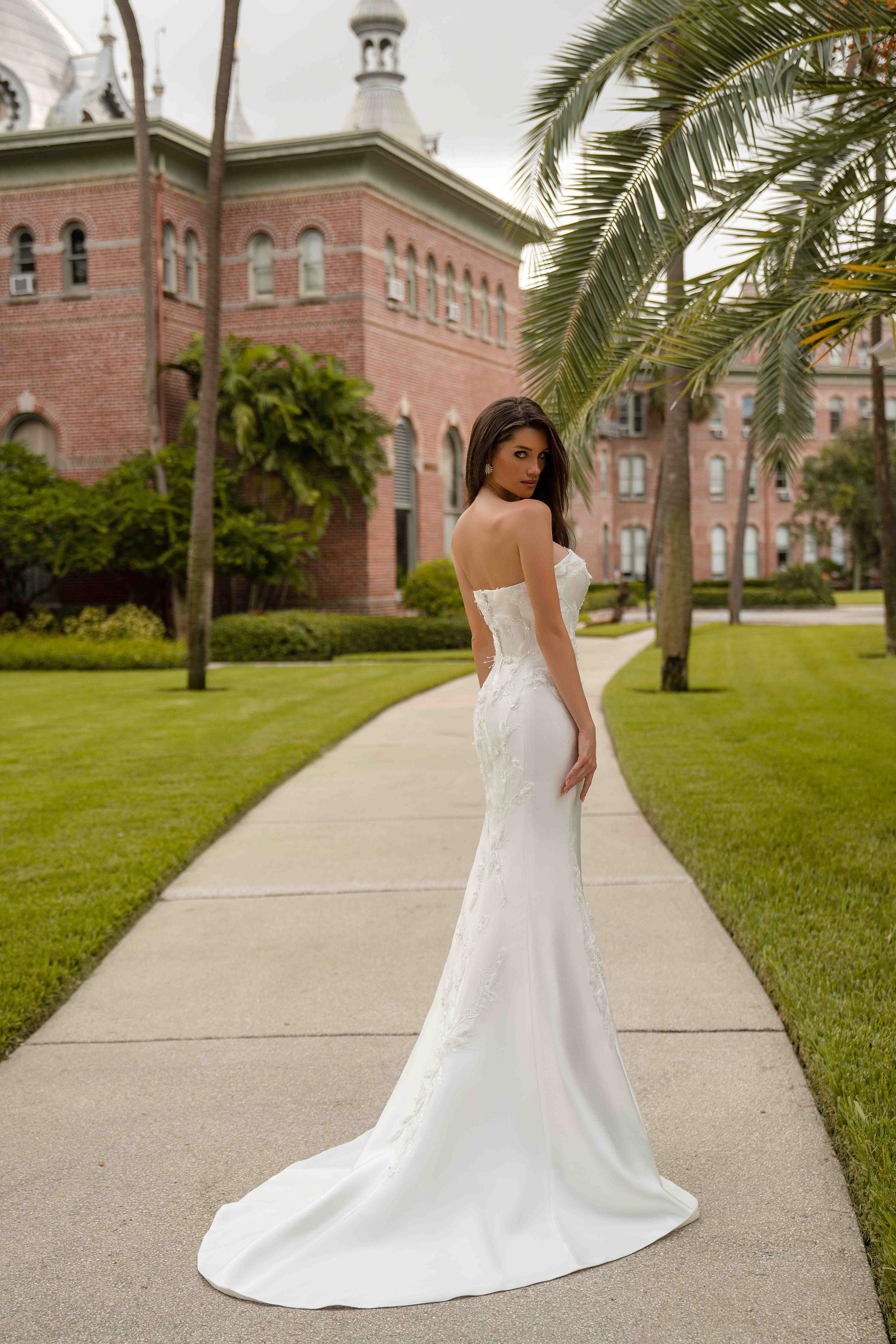 Ivory strapless sheath wedding dress with an open back, floral appliqués, and a sweeping train