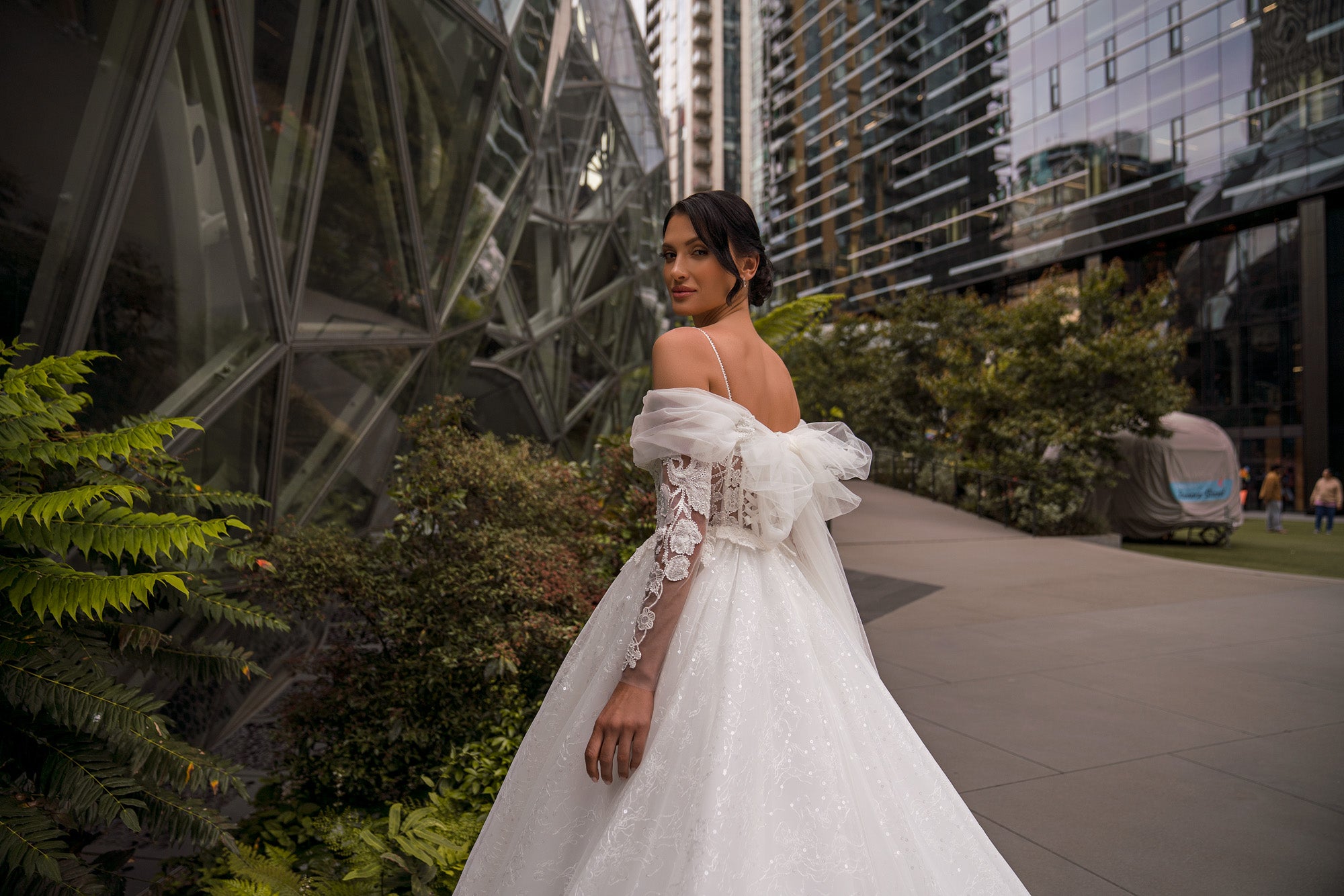 Ivory wedding dress with a lace back, thin shoulder straps, sheer off-the-shoulder sleeves, and A-line skirt