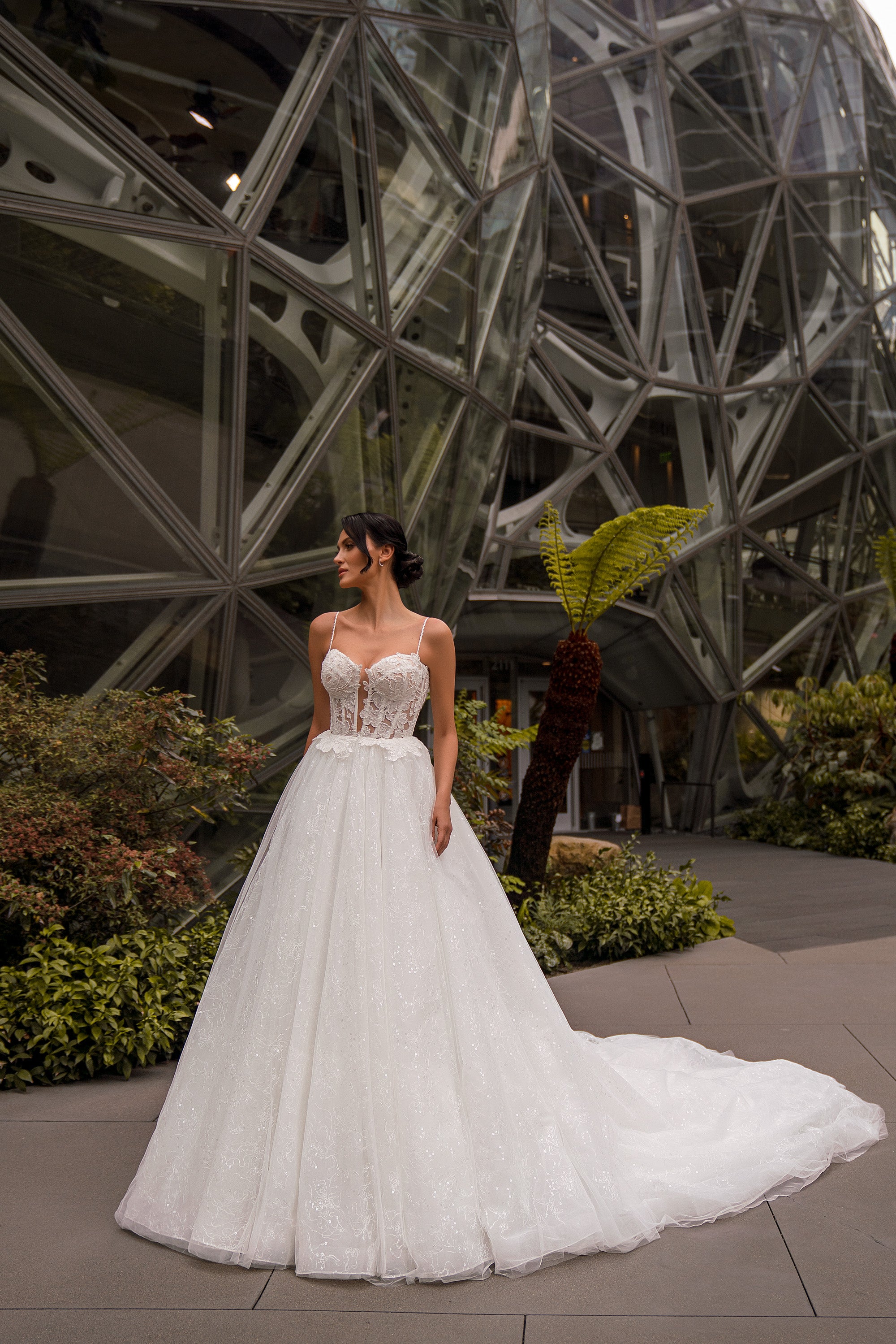 Ivory A-line wedding dress with a lace bodice, thin straps, sparkling full skirt, and sweeping train