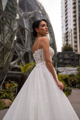 Ivory wedding dress with a floral lace back, delicate straps, and a sparkling A-line skirt