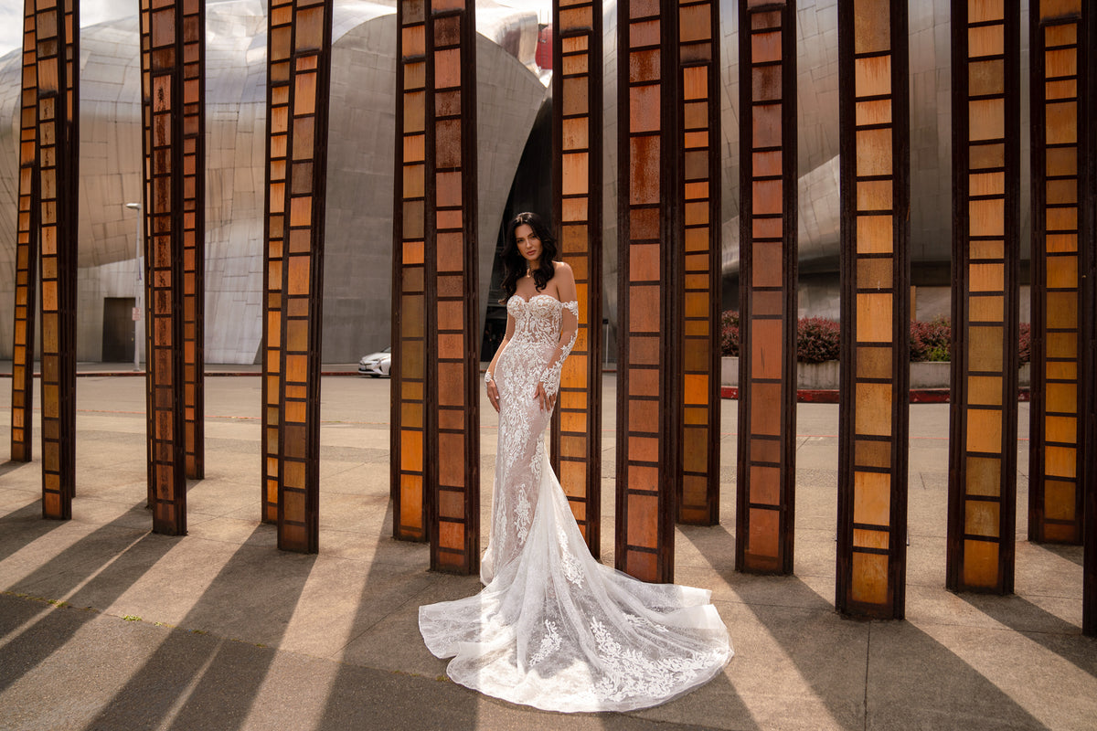 Full-length ivory wedding dress with a fitted mermaid silhouette, floral lace, and a flowing train