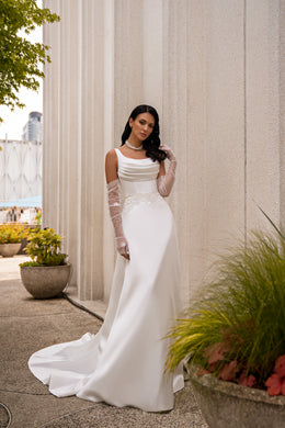 Ivory sheath wedding dress with draped scoop neckline, sheer sleeves, lace waist detail, and long train