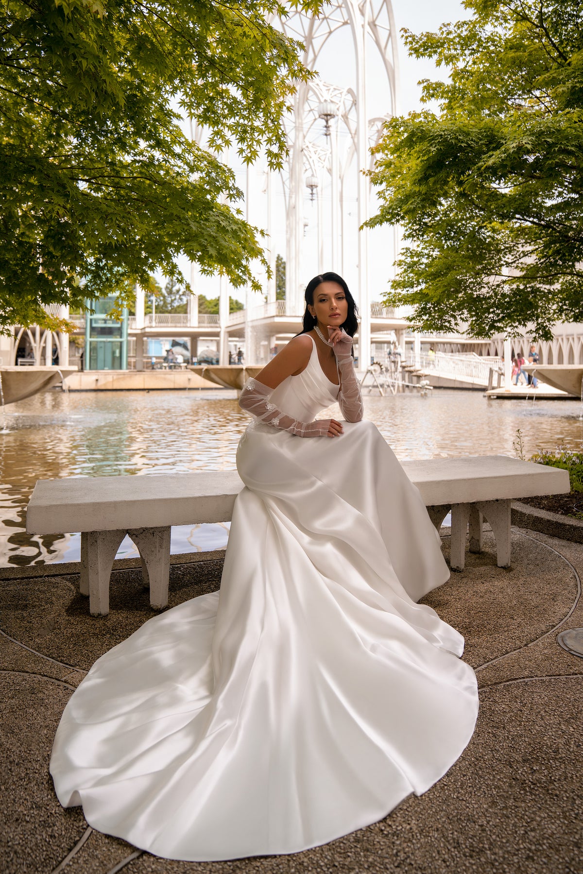 Ivory sheath wedding dress with sheer sleeves, smooth fitted skirt, and a wide flowing train