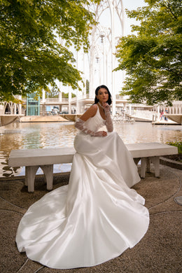 Ivory sheath wedding dress with sheer sleeves, smooth fitted skirt, and a wide flowing train