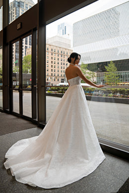 Ivory strapless wedding dress with a full skirt and sweeping train, shown from the back