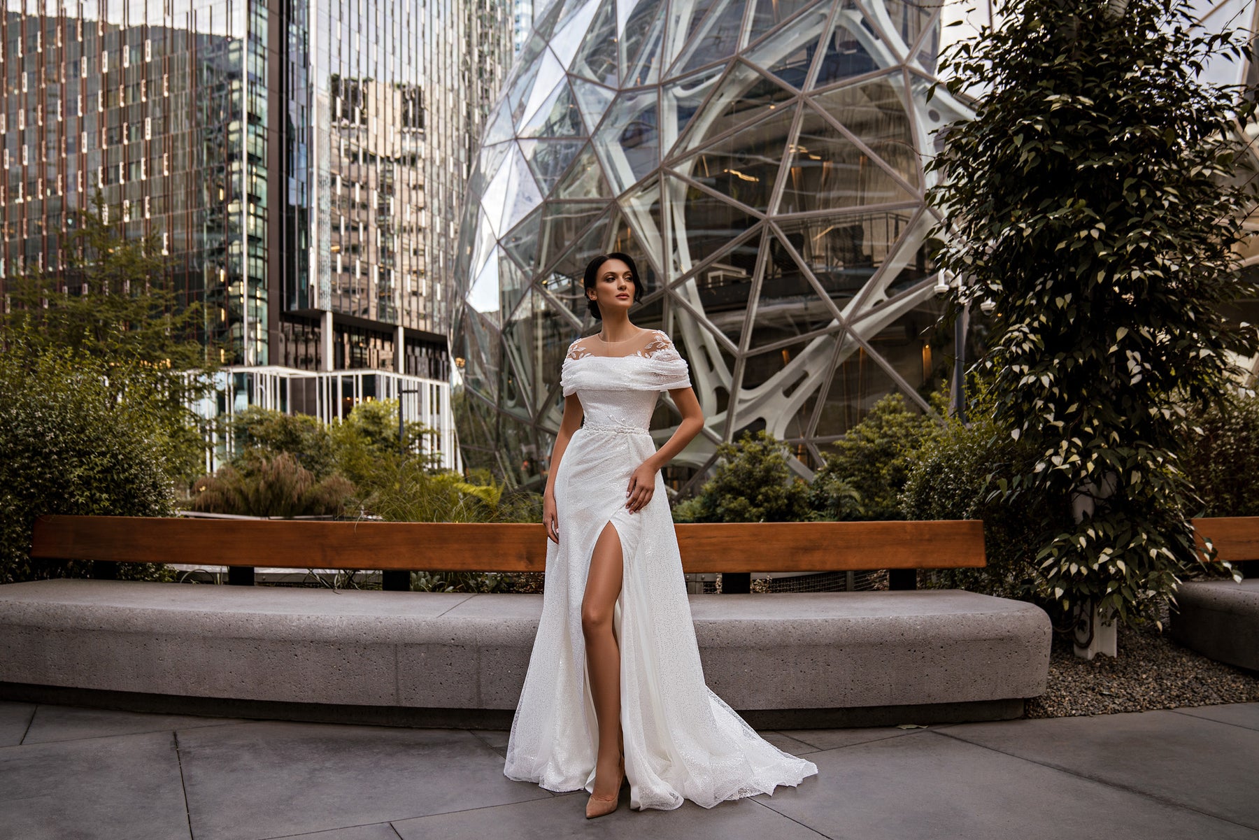 Ivory sheath wedding dress with an off-the-shoulder neckline, thigh-high slit, and sweeping train
