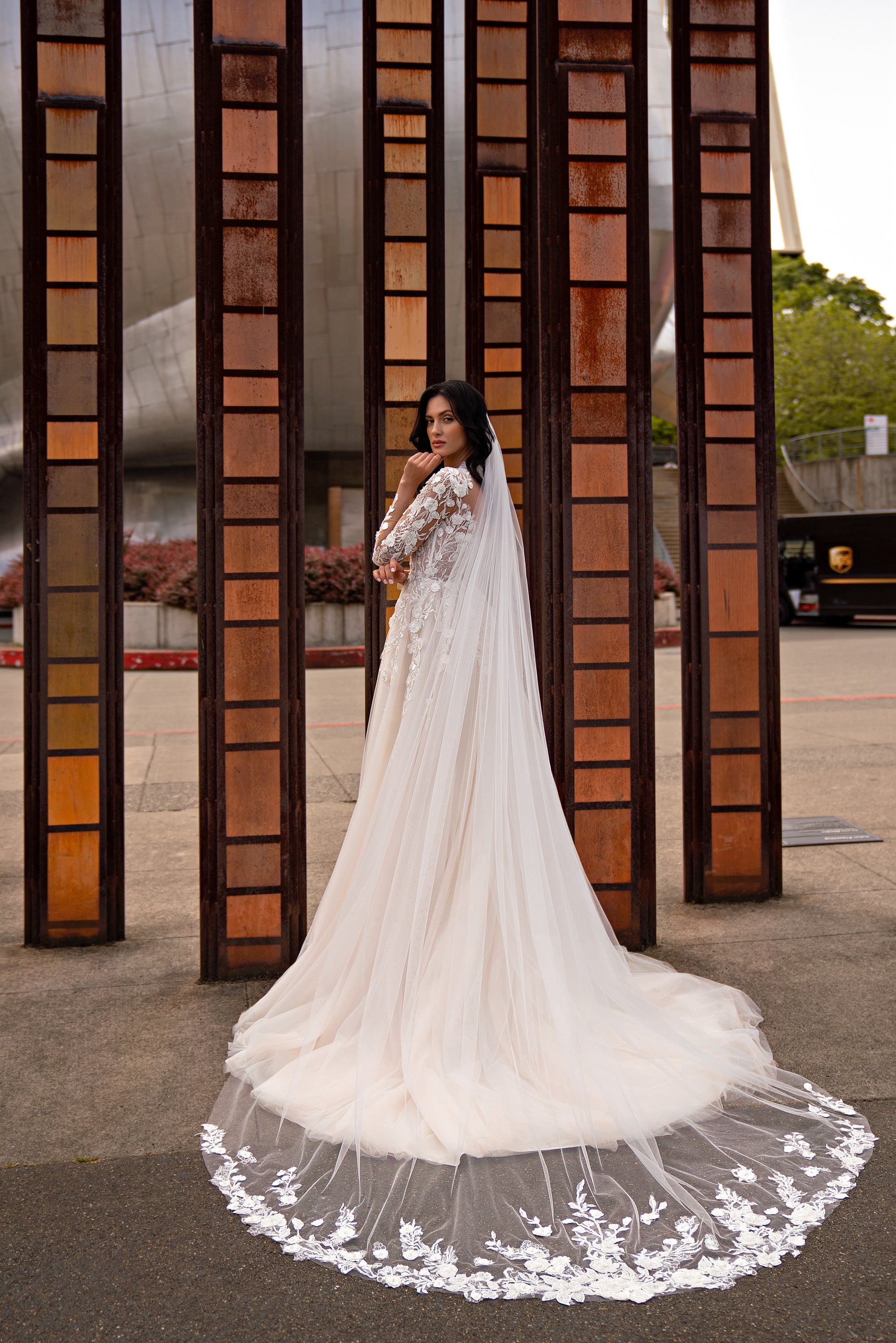 Ivory wedding dress with a flowing sheer cape, lace detailing, and a wide train