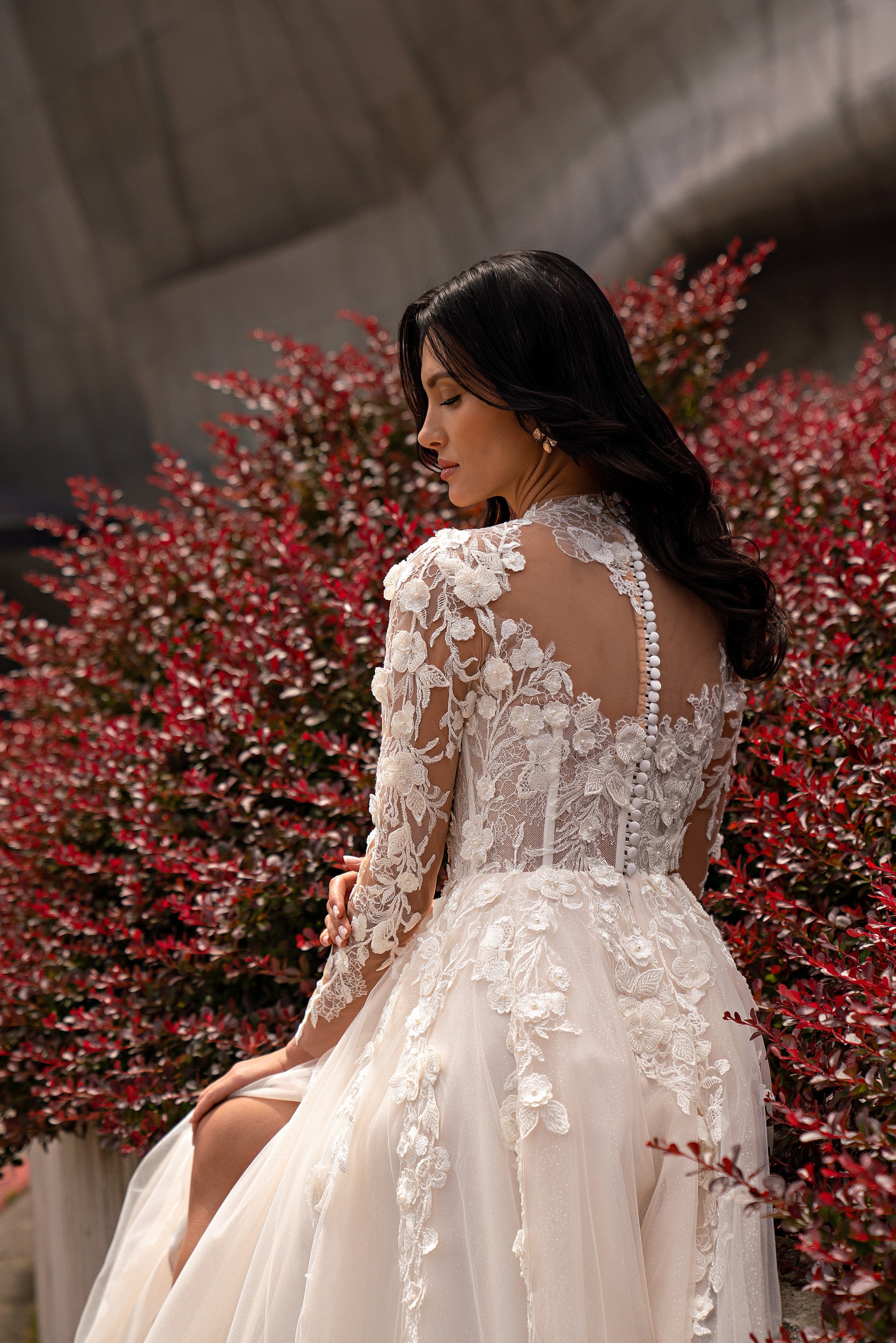 Back view of an ivory wedding dress with a sheer lace back, floral appliqués, and a flowing train