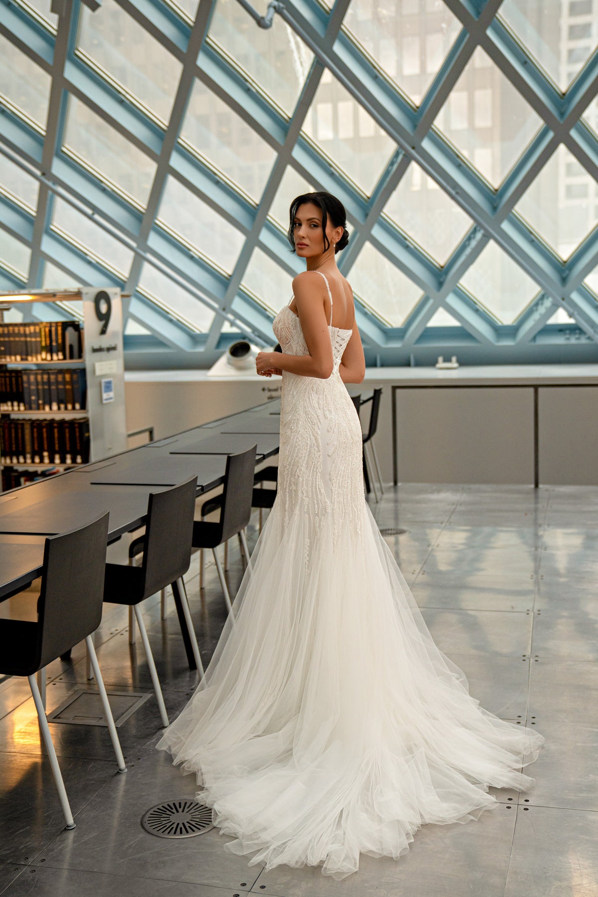 Open-back ivory mermaid wedding dress with thin straps, a fitted silhouette, and a long tulle train