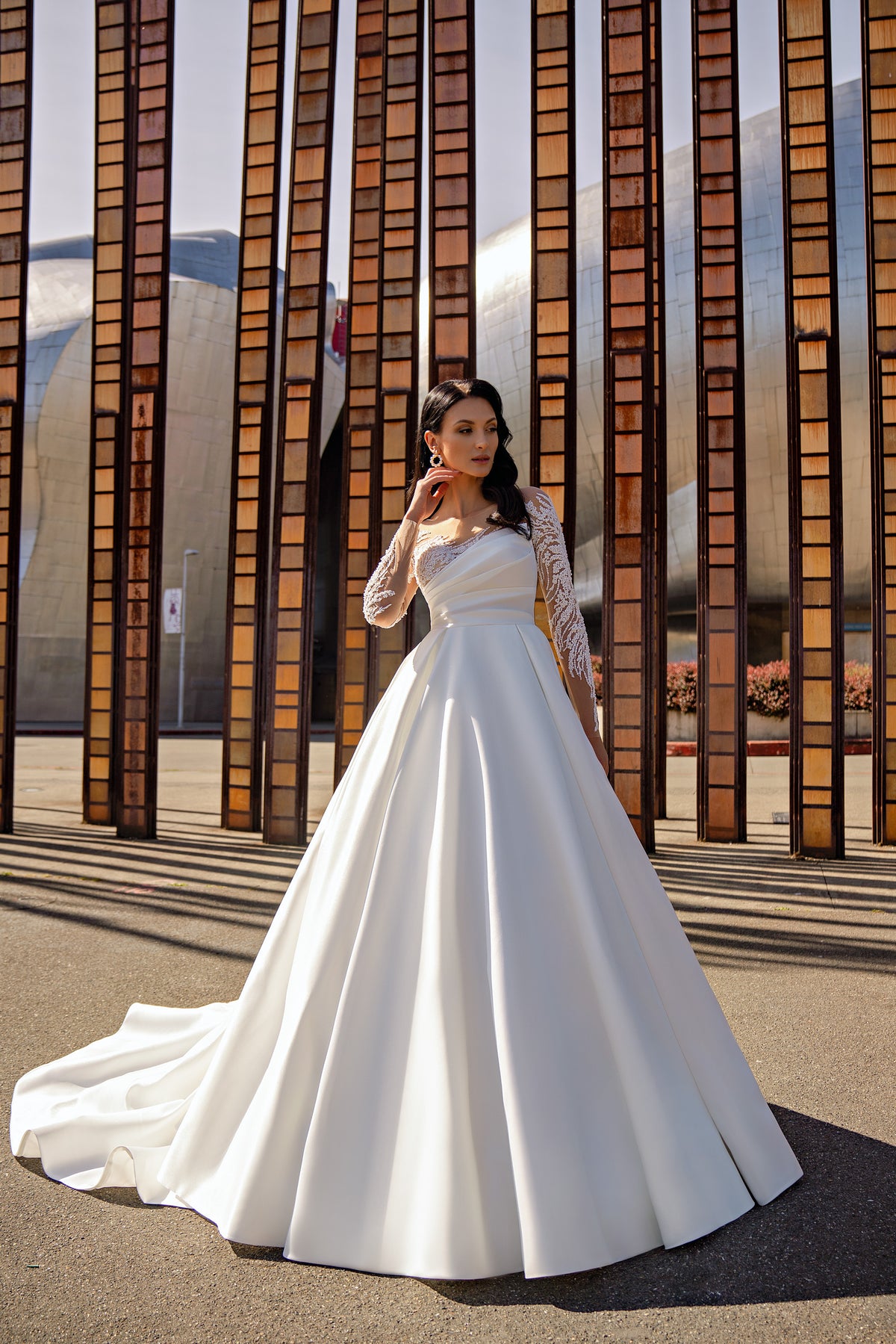 Ivory A-line wedding dress with sheer floral lace sleeves, an asymmetric neckline, and a long train