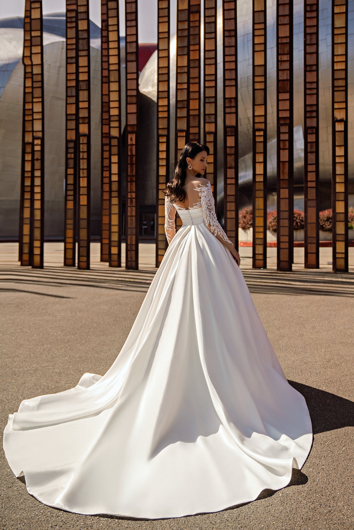 Ivory wedding dress with a full flowing skirt, lace long sleeves, and a sweeping train shown from behind