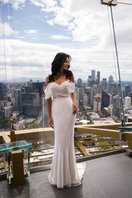 Ivory sheath wedding dress with an off-the-shoulder beaded bodice and subtle sweeping train