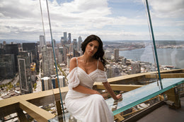 Ivory sheath wedding dress with a V-neckline, beaded bodice, and draped off-the-shoulder sleeves