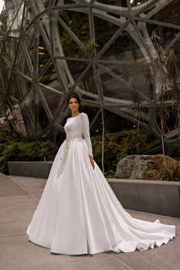 Ivory ball gown wedding dress with long sleeves, beaded appliqués, and a sweeping train