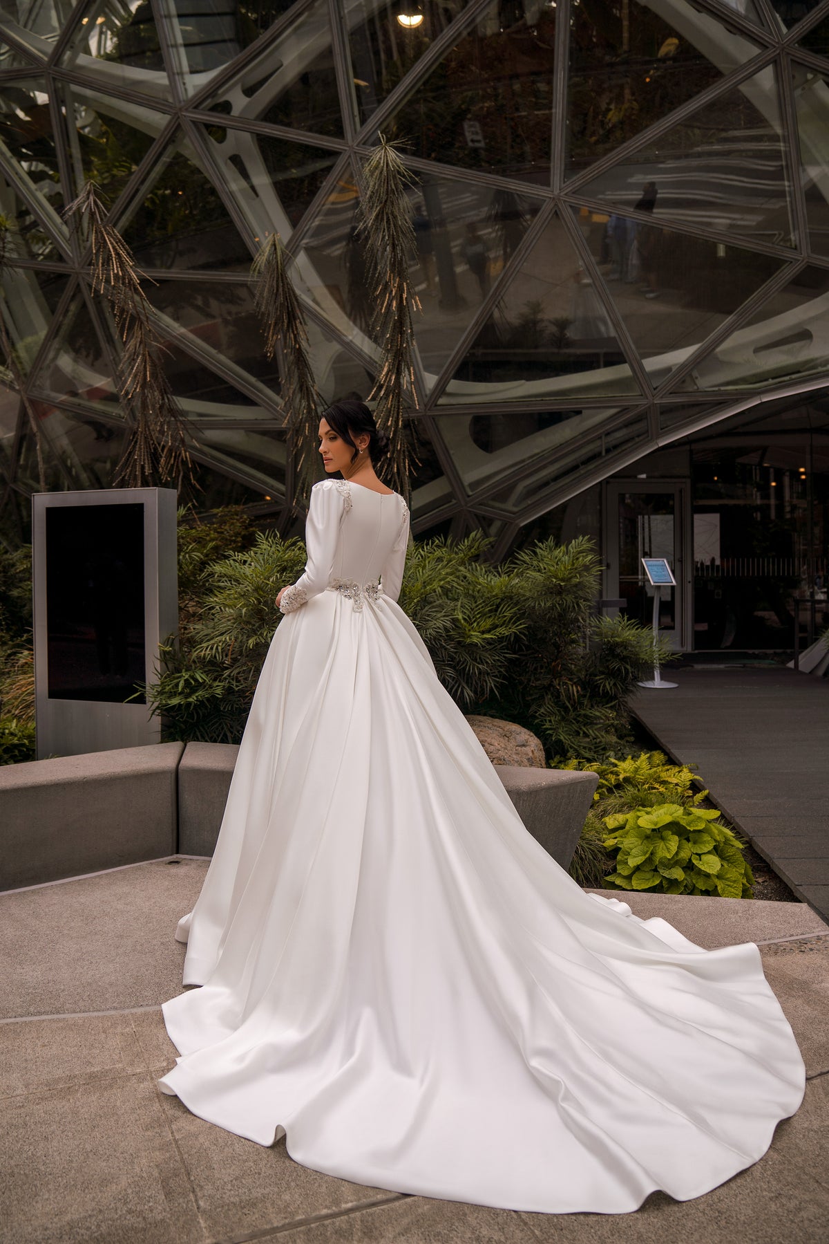 Back view of an ivory ball gown wedding dress with long sleeves and a broad, flowing train