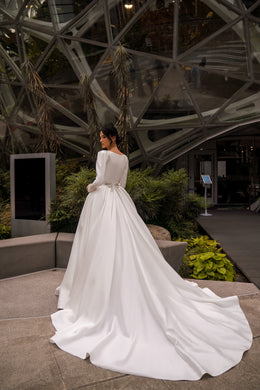 Back view of an ivory ball gown wedding dress with long sleeves and a broad, flowing train