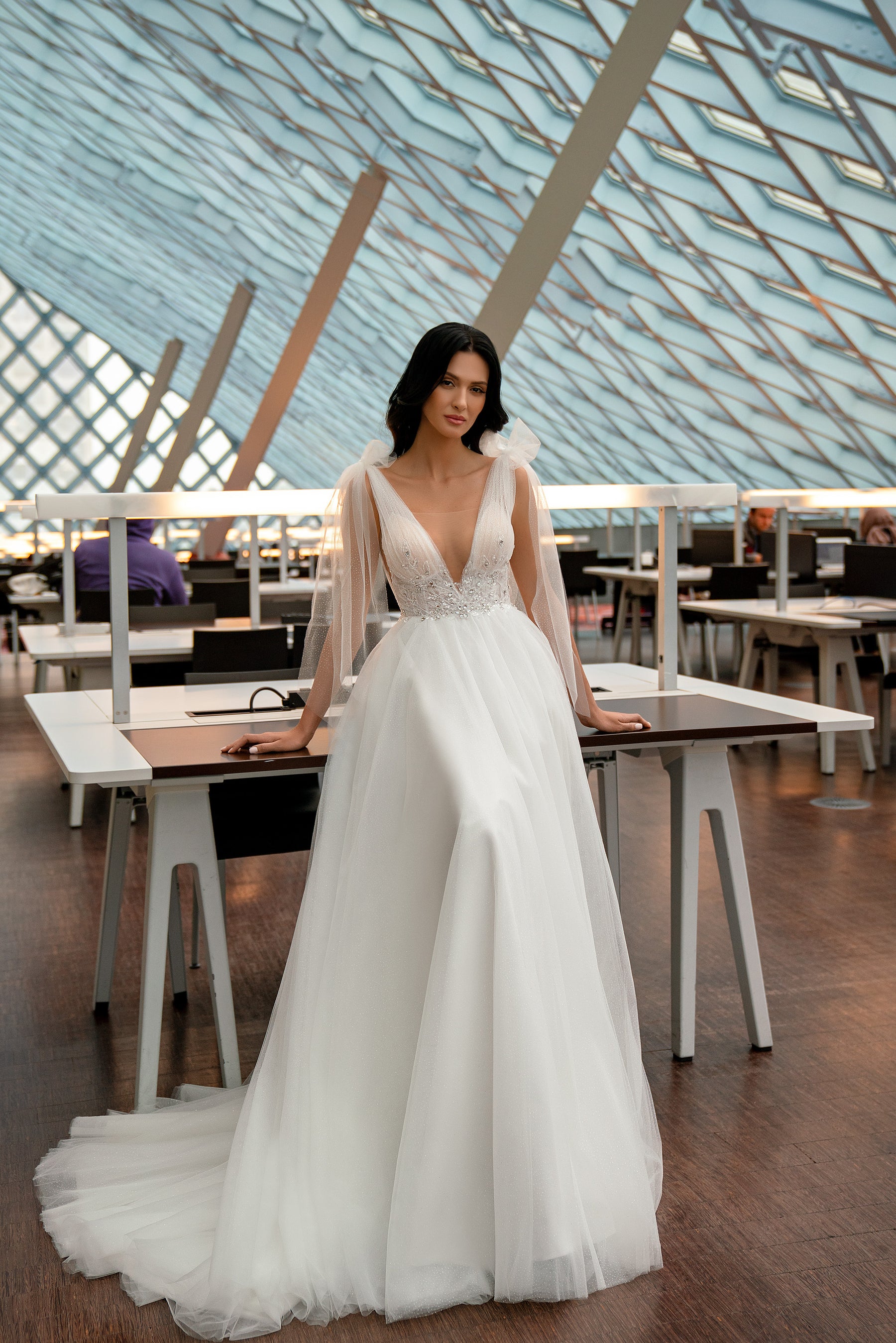 Ivory A-line wedding dress with a deep V-neck, beaded bodice, sheer sleeves, and full tulle skirt