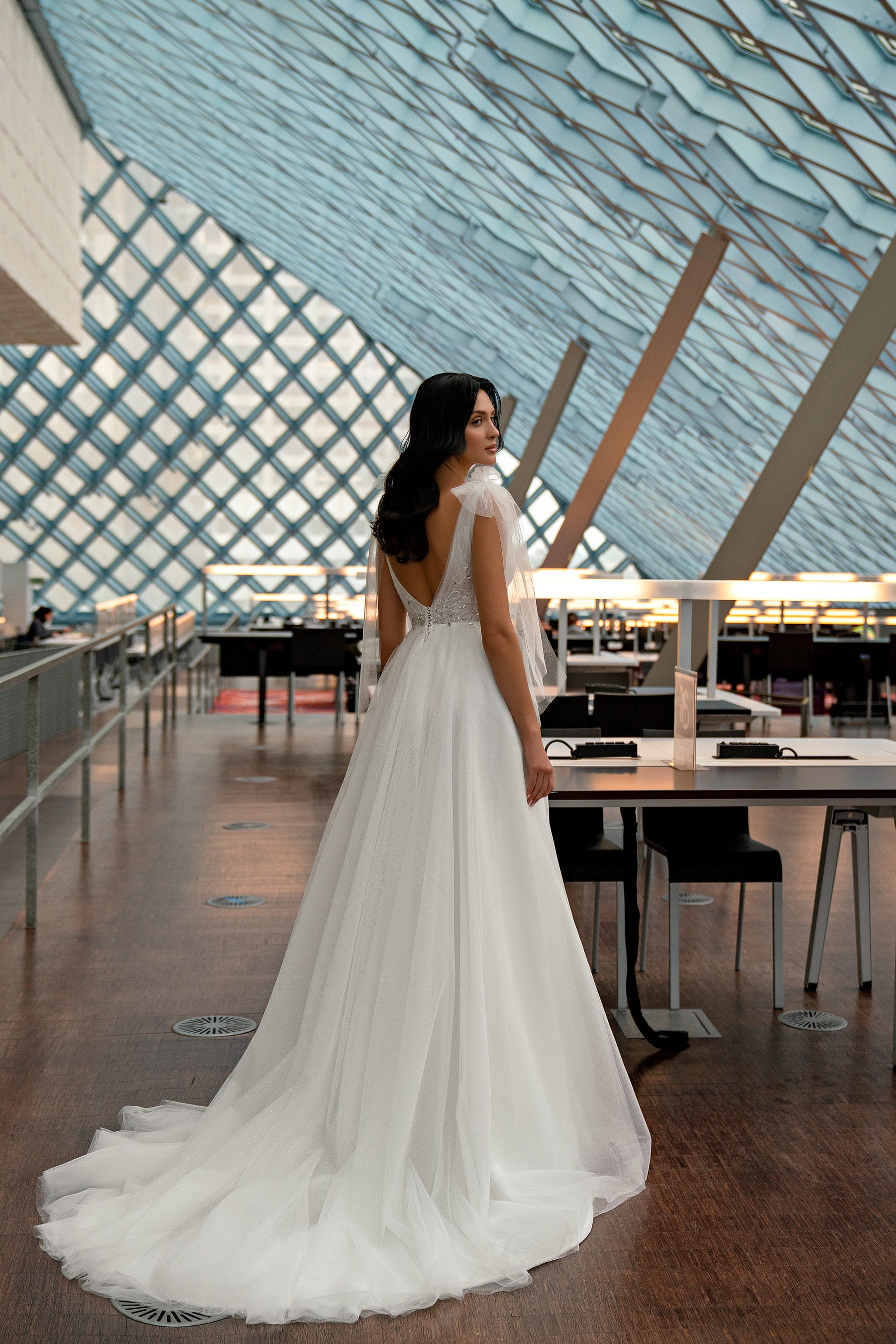 Open V-back wedding dress with delicate shoulder straps, a full tulle skirt, and sweeping train