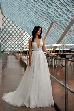 Ivory wedding dress with a beaded V-neck bodice, slender straps, and softly glittered full skirt