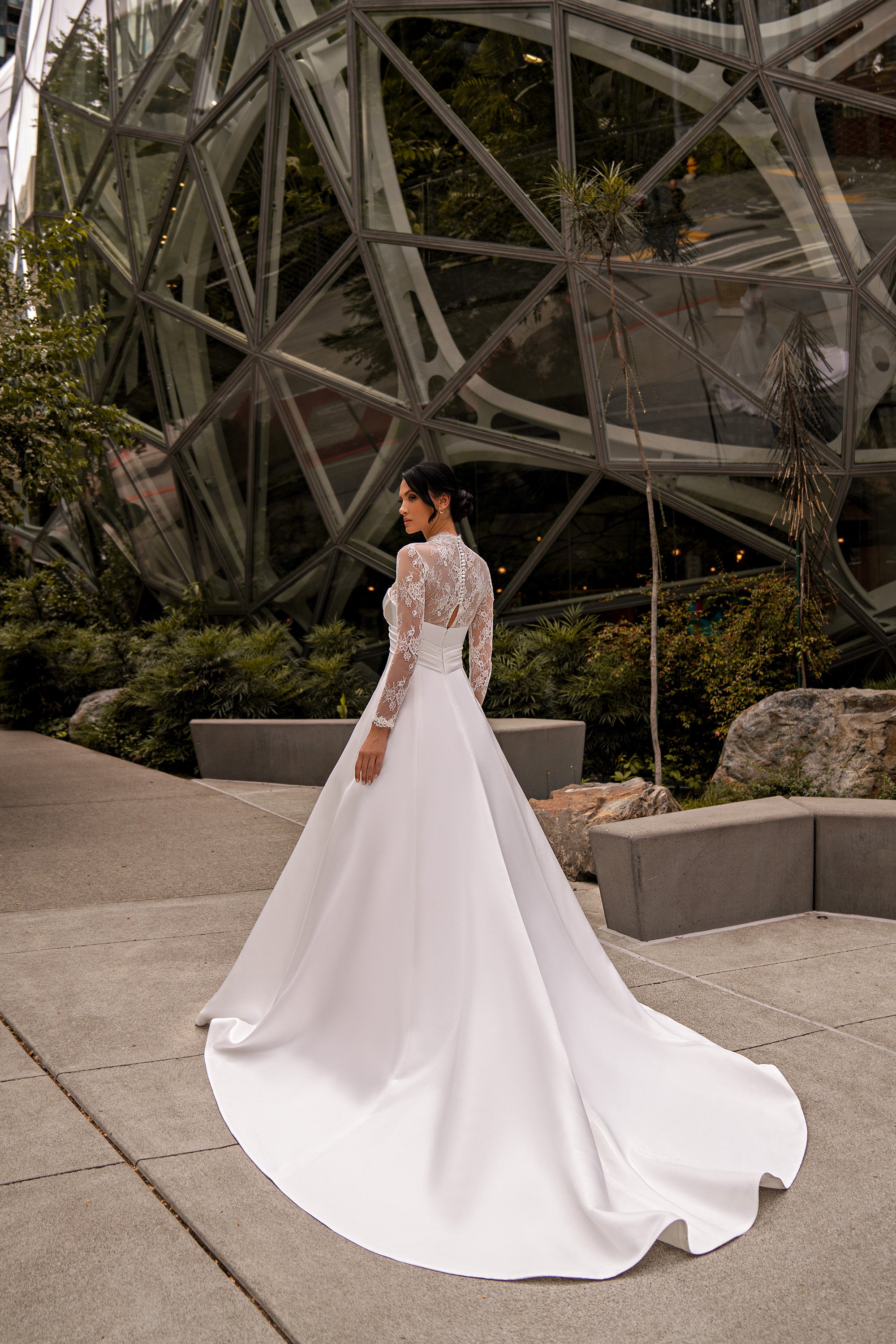 White A-line wedding dress with a lace-covered back, long sleeves, and a flowing train