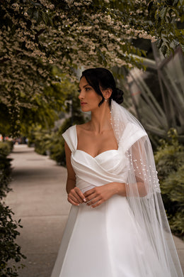 Close-up of an ivory wedding dress with a sweetheart neckline, draped bodice, and wide straps