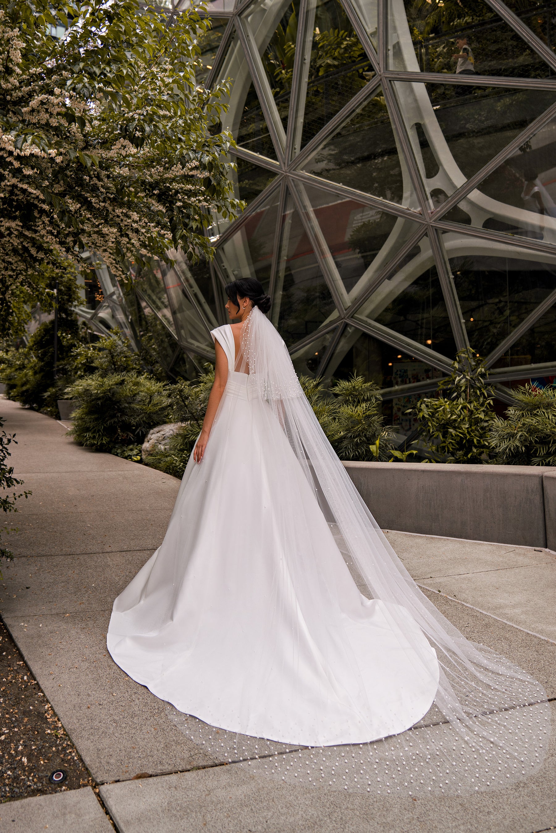 Rear view of an ivory wedding dress with lace at the shoulders and a long, pooling train