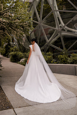 Rear view of an ivory wedding dress with lace at the shoulders and a long, pooling train