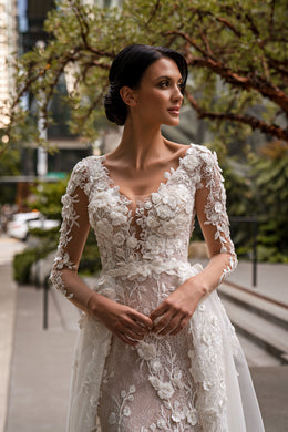 Close-up of floral lace appliqués on the fitted bodice and sheer sleeves of an ivory wedding dress