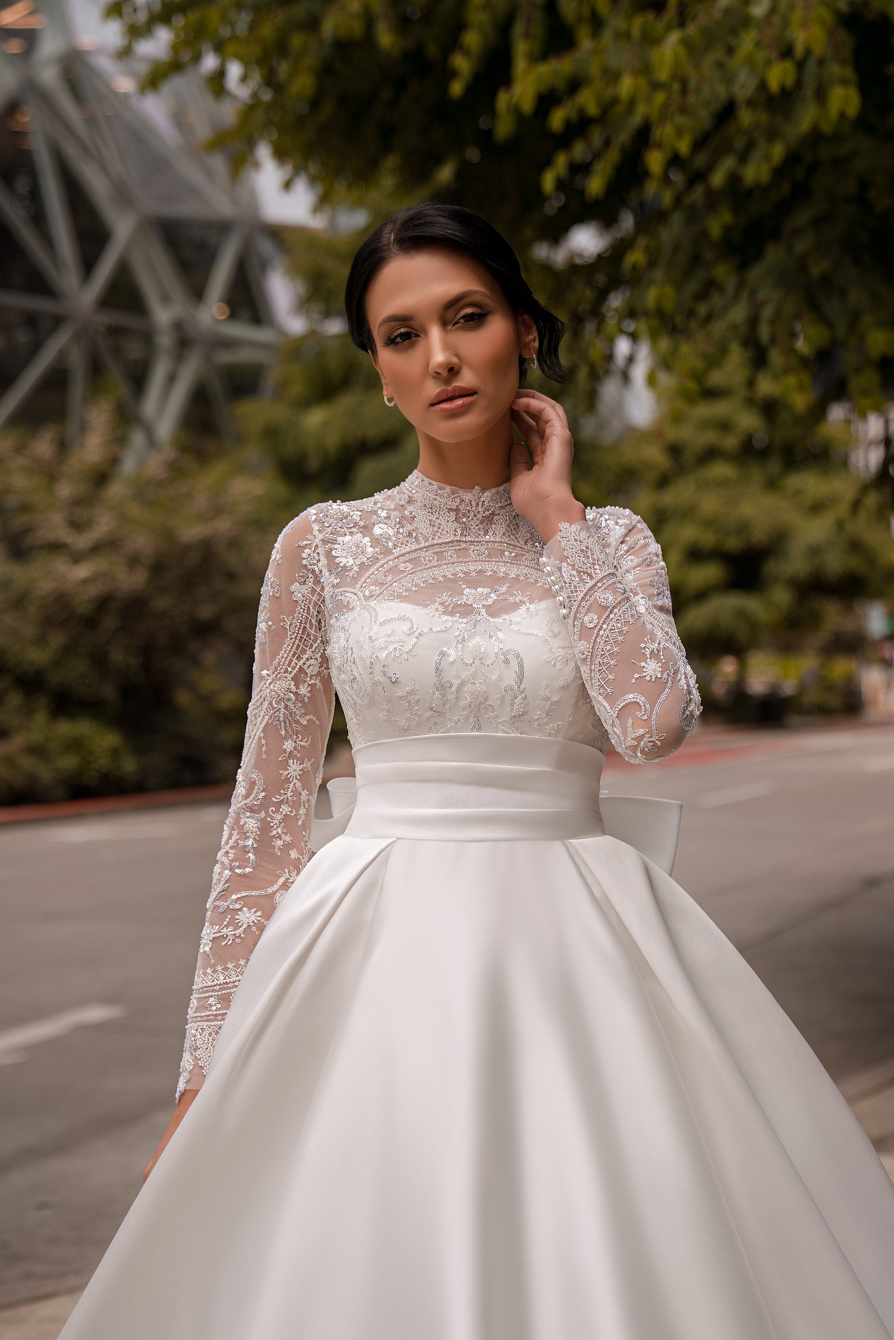 Close-up of an ivory wedding dress with a sheer lace high neckline, beaded floral bodice, and long sleeves