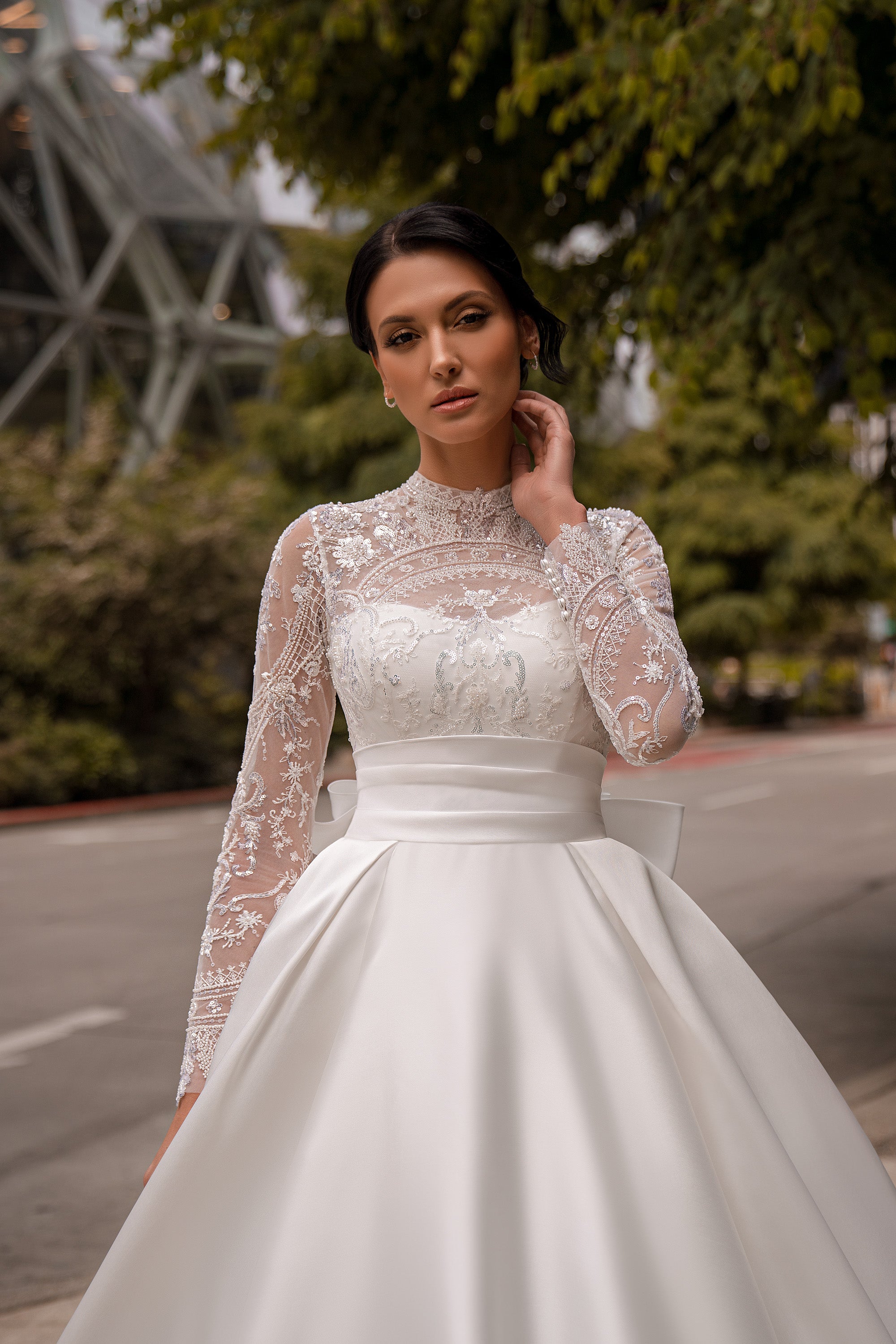 Close-up of an ivory wedding dress with a sheer lace high neckline, beaded floral bodice, and long sleeves