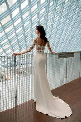 Back view of an ivory wedding dress with lace illusion bodice and a long fitted train