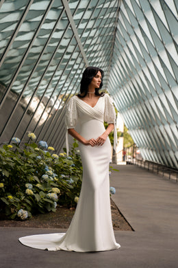 Ivory sheath wedding dress with a V-neckline, short puff sleeves, and a sweeping train