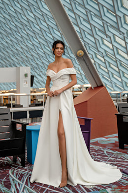 Ivory off-the-shoulder wedding dress with a wrapped bodice, high front slit, and flowing train