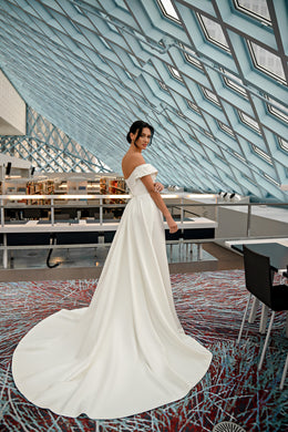 Ivory off-the-shoulder wedding dress with a flowing full-length train and softly draped A-line skirt