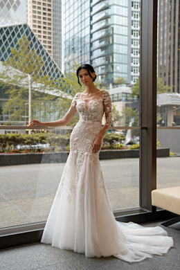 Ivory mermaid wedding dress with long lace sleeves, V-neckline, fitted bodice, and flowing train