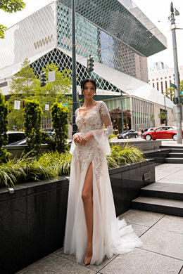 Ivory wedding dress with long illusion lace sleeves, floral appliqués, a high front slit, and train